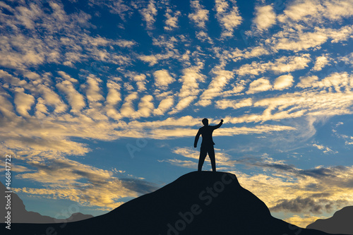 Victory concept, a silhouette of a man standing in the sunset sky.