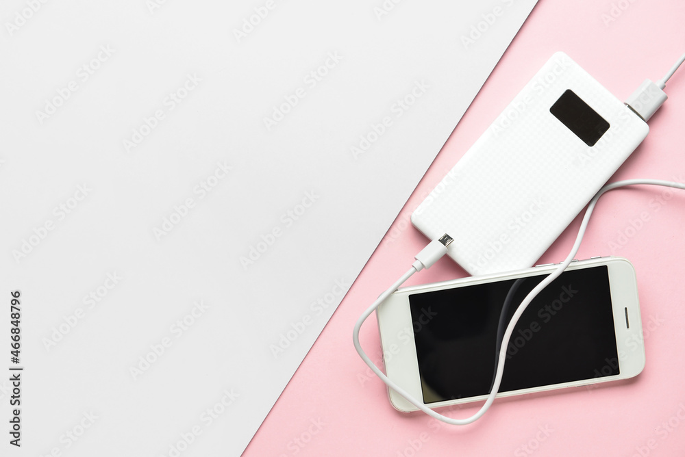 New power bank and mobile phone on color background