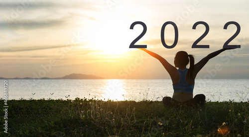 Happy new year 2022. Silhouette of girl on grass with beautiful sunset sky background.