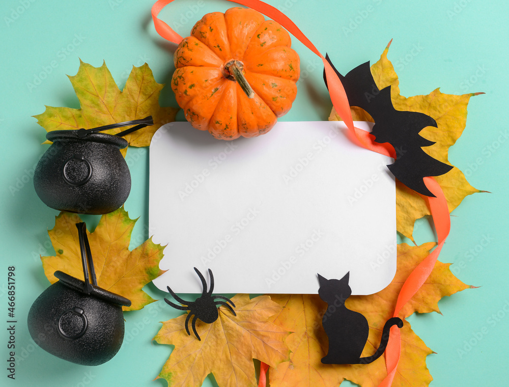 Blank paper sheet with Halloween decor and fallen leaves on blue