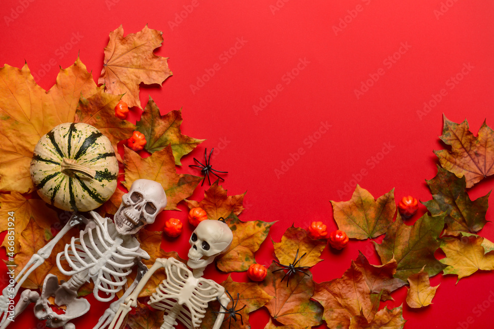 Skeletons with fallen leaves and Halloween pumpkins on red background