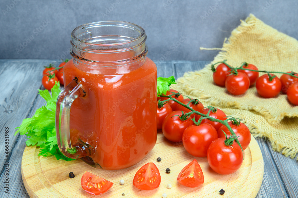 A jar of tomato juice, tomatoes and allspice on a cutting board and tomatoes on a coarse linen cloth lie side by side A jar of tomato juice, tomatoes and allspice on a cutting board and tomatoes on a coarse linen cloth lie side by side