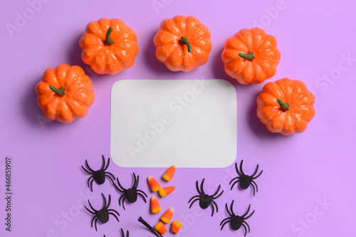 Blank paper sheet with pumpkins  spiders and candies on violet background