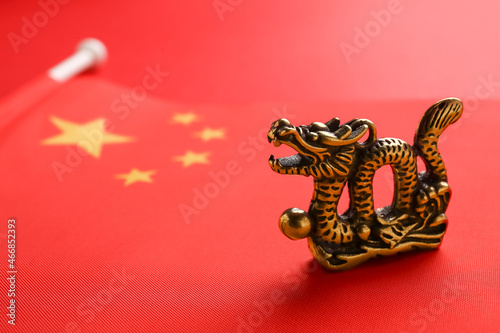 Figurine of dragon and Chinese flag on color background