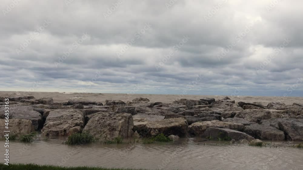 Waves crashing into the rocky shoreline along Lake Michigan. White cap waves crashing into rocks. Rippling water running along barrier. Waves crashing into the rocky shoreline along Lake Michigan. White cap waves crashing into rocks. Rippling water running along barrier.