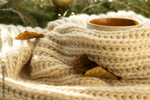 Cup of autumn coffee, tea or hot chocolate, fall leave on a warm scarf. Drink for cold rainy days. Seasonal, morning coffee. Sunday relaxing, hygge, still life concept. Selective focus