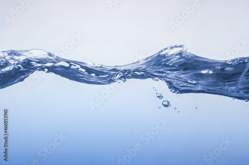 Water splash on blue background. Aqua flowing in waves and creating bubbles. Drops on the water surface feel fresh and clean.