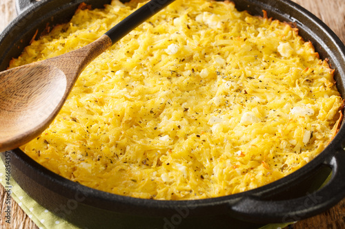 Bulgarian potato pie Patatnik with onions, cheese and eggs close-up in a frying pan on the table. horizontal photo