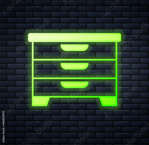 Glowing neon Chest of drawers icon isolated on brick wall background. Vector