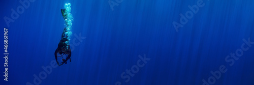 Canvas-taulu Blue background banner with a scuba diver entering water in a vertical position