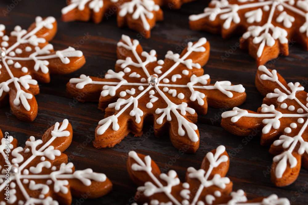 Christmas background with homemade snowflake shape gingerbread cookies on wooden background. New Year celebration traditions concept.