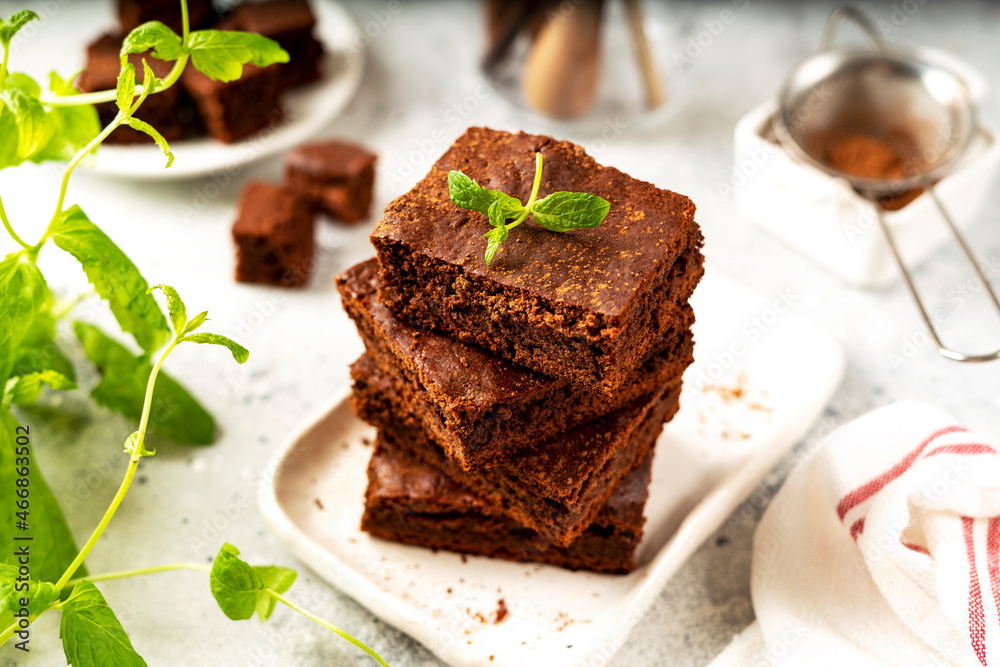 Chocolate brownie pie slices in a white plate on a light background. Homemade blondie bars traditional American dessert closeup