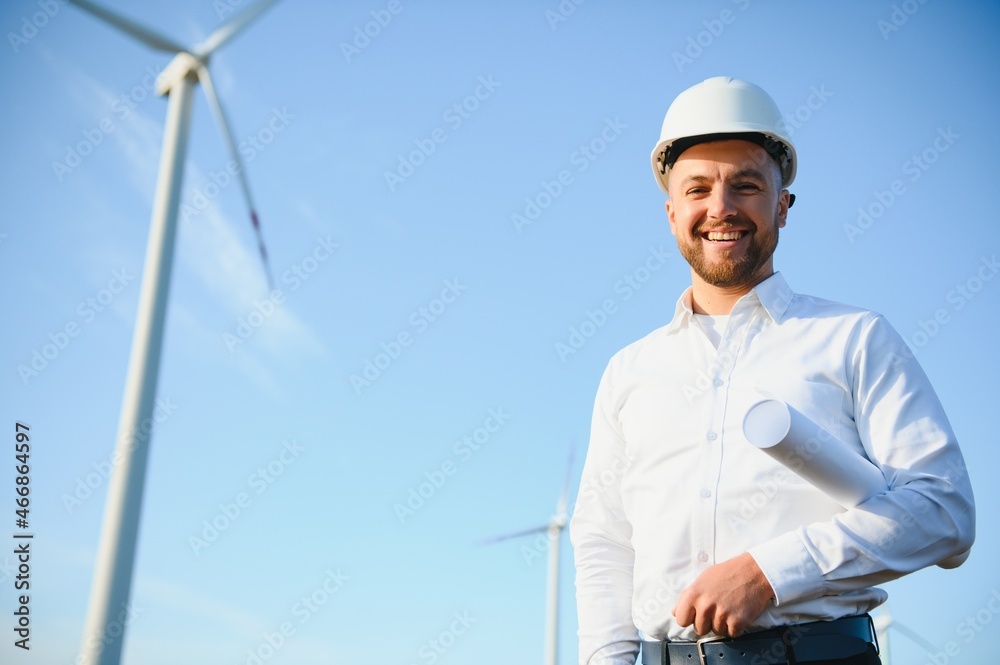 Engineer is checking energy production on wind turbine. Worker in windmills park in helmet. Engineer is checking energy production on wind turbine. Worker in windmills park in helmet.