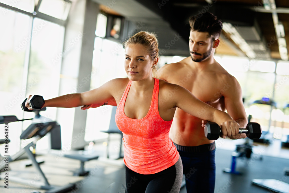 Personal trainer helping a woman to working out in gym. Sport people healthy lifestyle concept Personal trainer helping a woman to working out in gym. Sport people healthy lifestyle concept