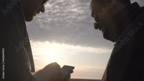 Businessman and agronomist are working with the help of agro application on smartphone. The wheat harvest is ripening in the field. Smart ago business.