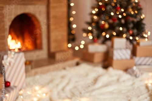 Indoor shot of festive living room with white soft carpet on the middle of room, decorated with Christmas tree, fireplace and stack of new year presents.