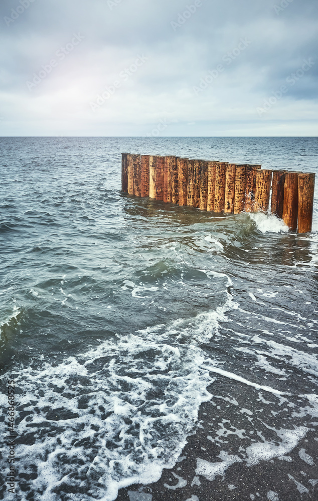 Wooden breakwater seen from a beach, color toning applied.