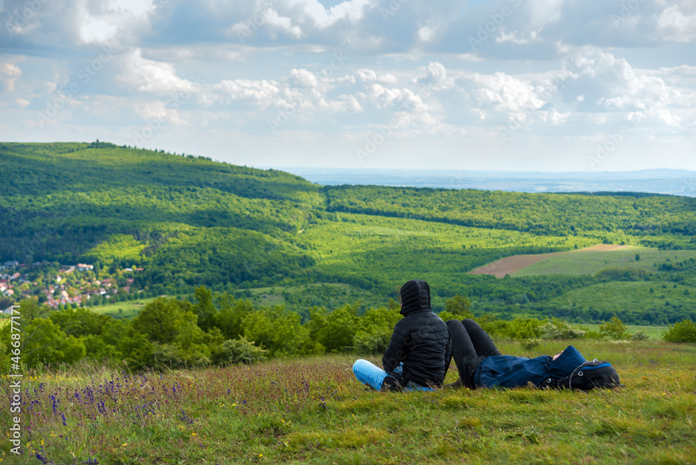 Hikers relaxing sitting on the ground against green hills