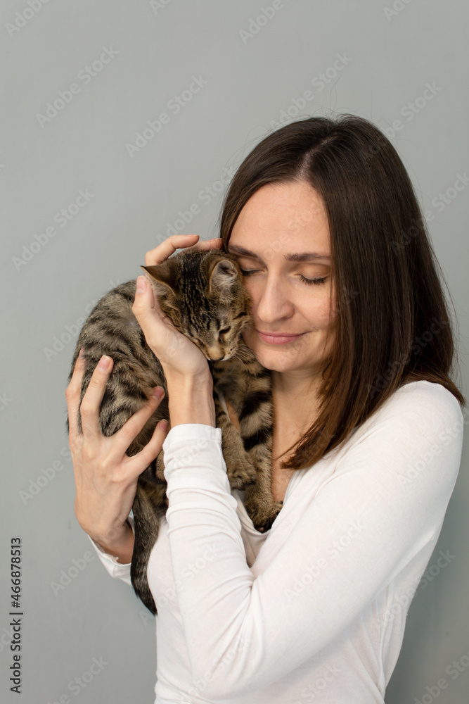young woman in a white shirt is holding a kitten in her arms. young woman in a white shirt is holding a kitten in her arms.