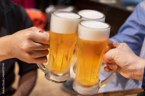 飲食店でジョッキの生ビールを乾杯する人たち