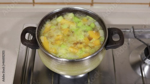 Pumpkin soup preparation. Saucepan with chopped celery and cubed pumpkin in boiling water