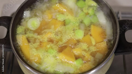 Pumpkin soup preparation. Saucepan with chopped celery and cubed pumpkin in boiling water