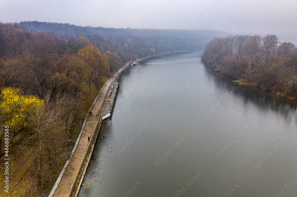 Naklejka premium autumn green river and yellow park on a cloudy autumn day filmed from a drone 