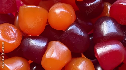 Close-up texture of red, orange and purple multivitamin gummies on white background. Healthy lifestyle concept