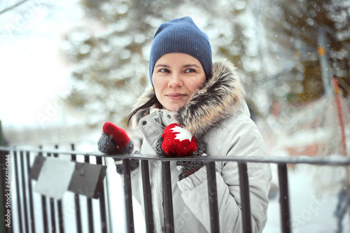 smiling young woman in a winter forest in mittens with maple leaves, at a ski resort. a girl in a blue hat and a white jacket. The concept of Canada. #466886144