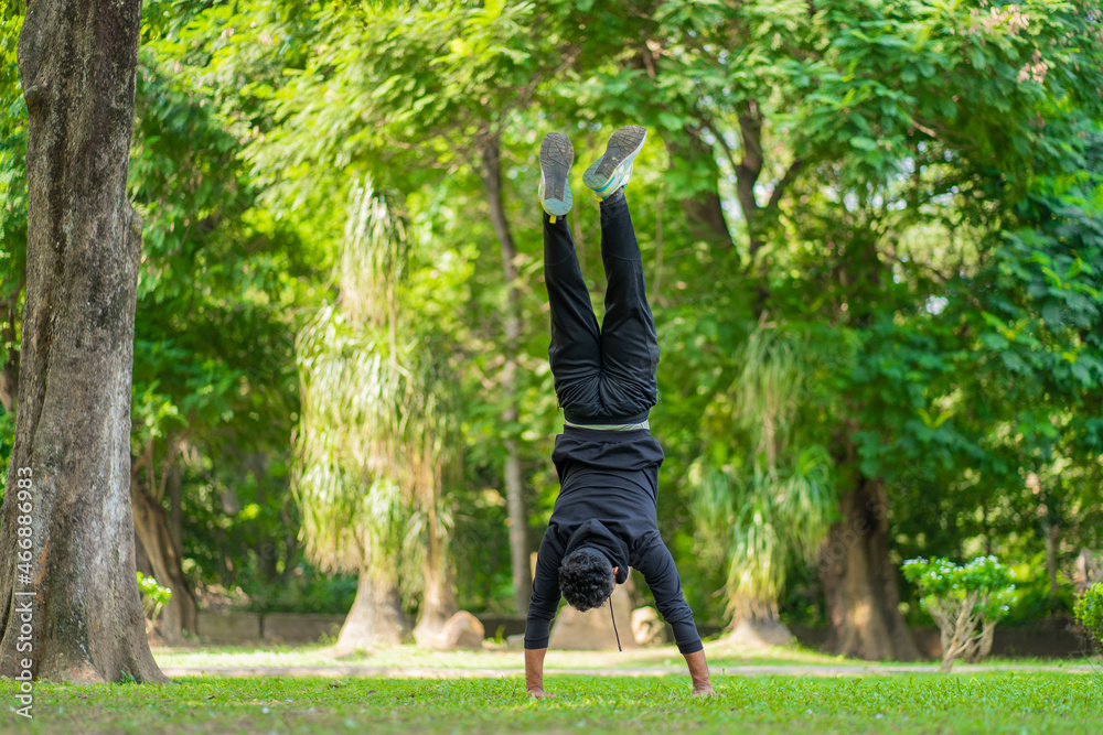 A young guy doing a handstand in the park