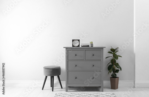 Schilderij op canvas Elegant room interior with stylish chest of drawers, pouf and houseplant
