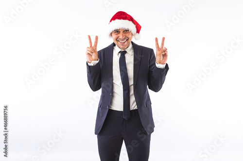 Businessman dressed in suit, tie and Santa Claus Christmas hat, having fun, on white background. Christmas celebration concept. © Davidbenito
