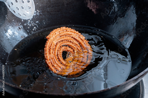 Homemade Preparation of Indian Traditional Snack Chakli consumed during diwali festival, a spiral shaped crisp deep fried snack, It is known as Chakali, Murkoo, Muruku and Murukku. photo
