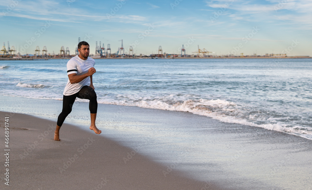 hombre fuerte atletico moreno indio pakistani corre hace deporte en una playa de arena con un fondo de un puerto maritimo hombre fuerte atletico moreno indio pakistani corre hace deporte en una playa de arena con un fondo de un puerto maritimo
