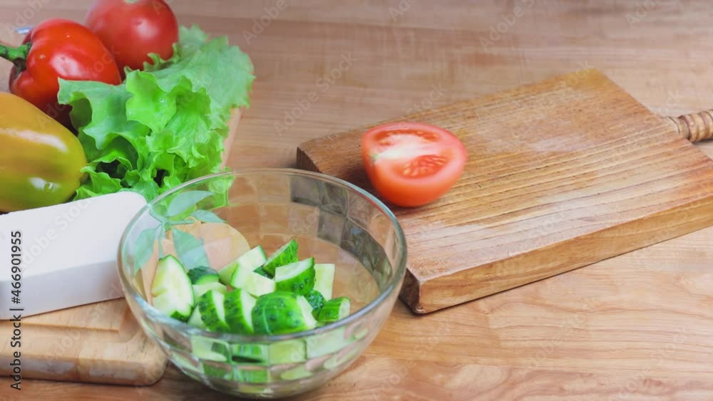 Cutting fresh tomato on a wooden chopping board, cooking a greek salad, vegetarian food Cutting fresh tomato on a wooden chopping board, cooking a greek salad, vegetarian food