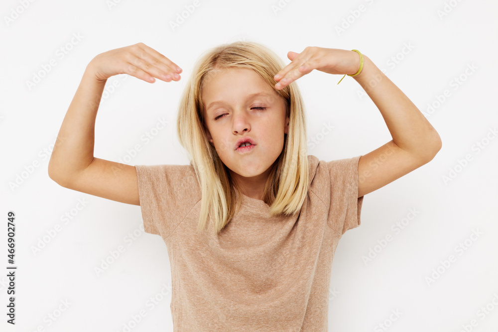 Positive little girl in a beige t-shirt isolated background Positive little girl in a beige t-shirt isolated background