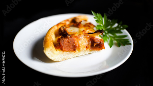a slice of Italian pizza on a white plate with some tasty topping on it. a studio shot of a delicious food isolated on black.