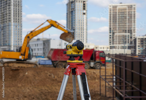 Photo of a level at the construction site of multi-storey buildings with a yellow excavator and an red truck on the street in the city