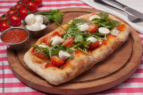 italian pizza with mozzarella, tomatoes and arugula