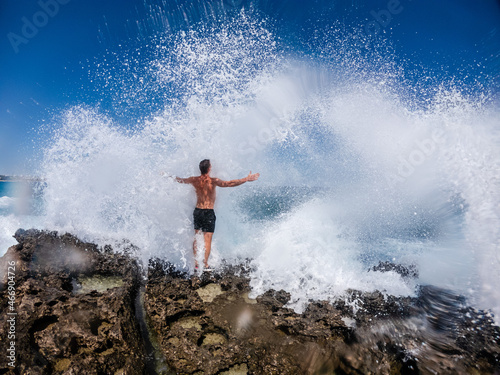 Man standing on cliff during storm in sea. Splashes of ocean waves