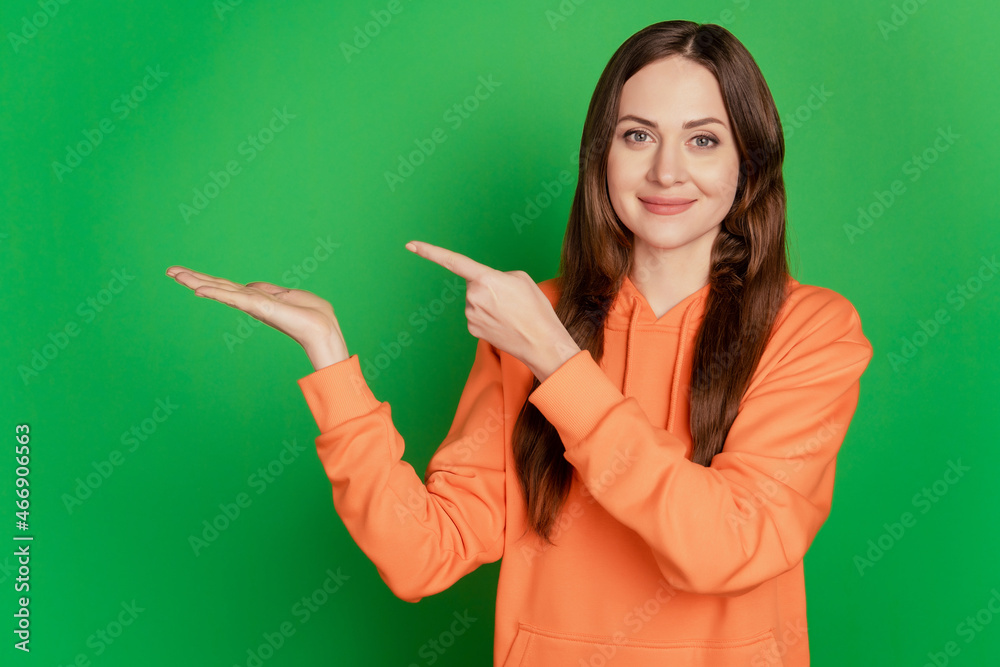 Portrait of reliable teen lady open palm hold blank space indicate finger on green background Portrait of reliable teen lady open palm hold blank space indicate finger on green background
