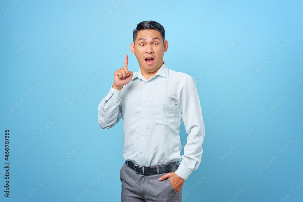 Fototapeta premium Excited young handsome businessman having a creative idea and looking camera on blue background
