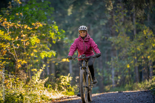 ympathetic active senior woman, riding her electric mountainbike in the colorful autumn forests of the Bavarian Alps near Oberstaufen, Germany
