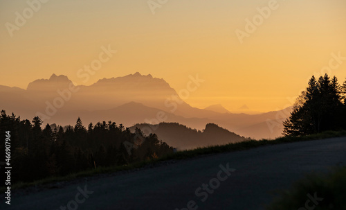 active woman riding her electric mountain bike at sunset in front of the awesome silhouette of Mount Saentis, Appenzell switzerland