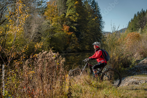 ympathetic active senior woman, riding her electric mountainbike in the colorful autumn forests of the Bavarian Alps near Oberstaufen, Germany