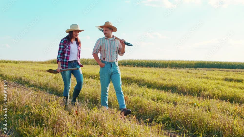 Two male and female agronomists walking through the professional ecological field exterior. Farm and modern business concept Two male and female agronomists walking through the professional ecological field exterior. Farm and modern business concept