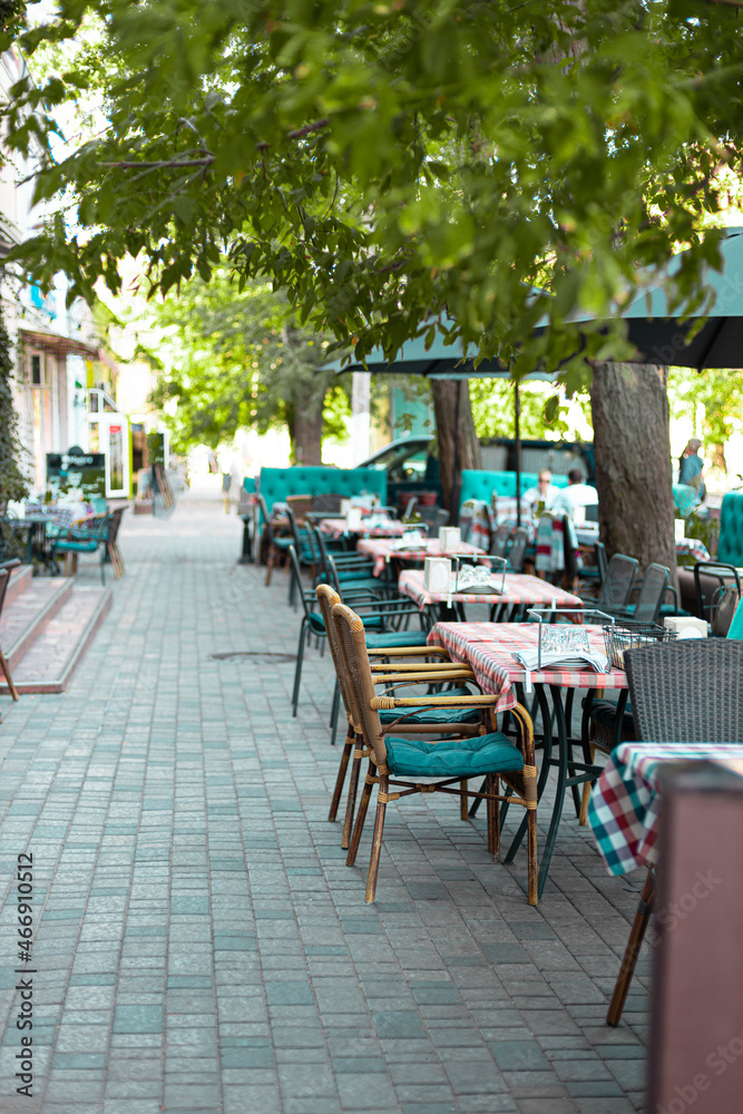 Vase with fresh flowers on a napkin, decorates a table of a street cafe on a summer day. Empty street cafe or restaurant tables with chairs on street