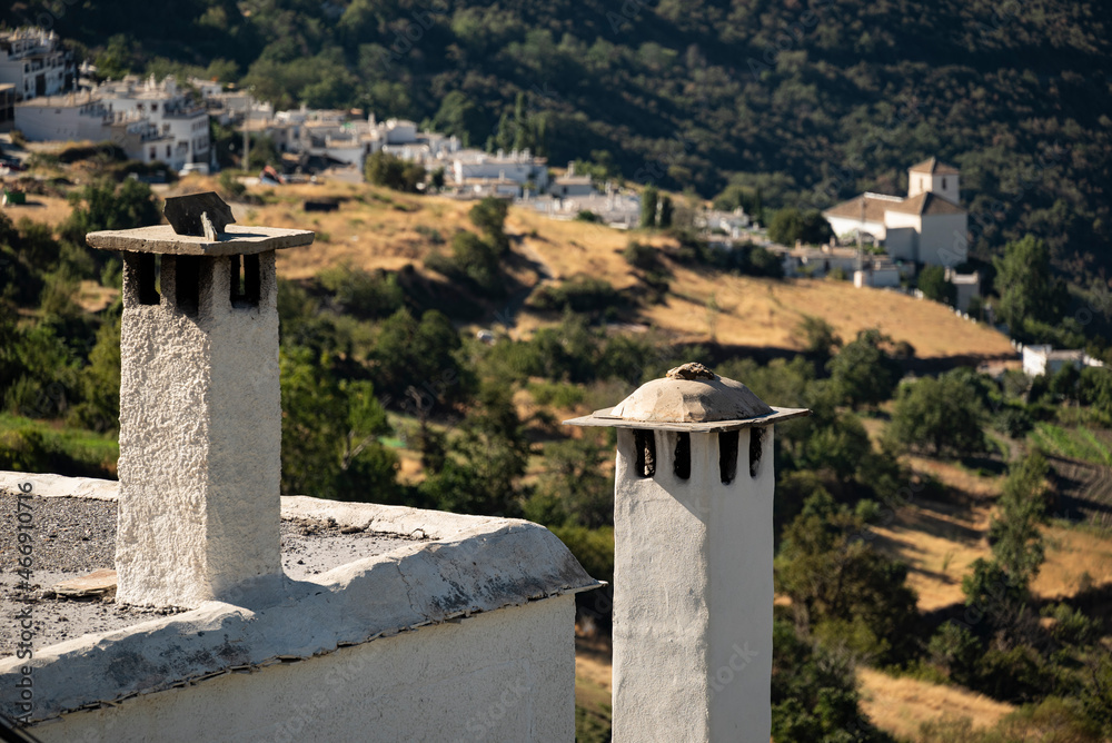 Typical chimneys on a rooftop in Capileira, with the village of Bubión in the background, Las Alpujarras, Sierra Nevada National Park, Andalusia, Spain