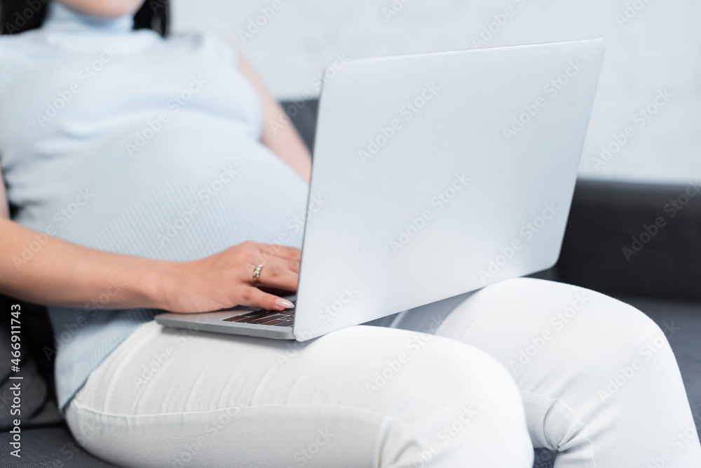 cropped view of blurred pregnant woman typing on laptop at home cropped view of blurred pregnant woman typing on laptop at home