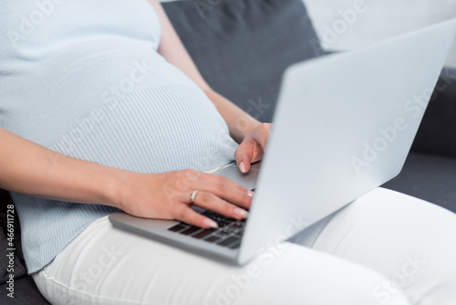cropped view of pregnant woman typing on blurred laptop at home